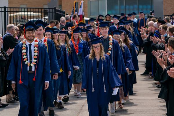 Group of successful college students celebrating graduation with caps and gowns.